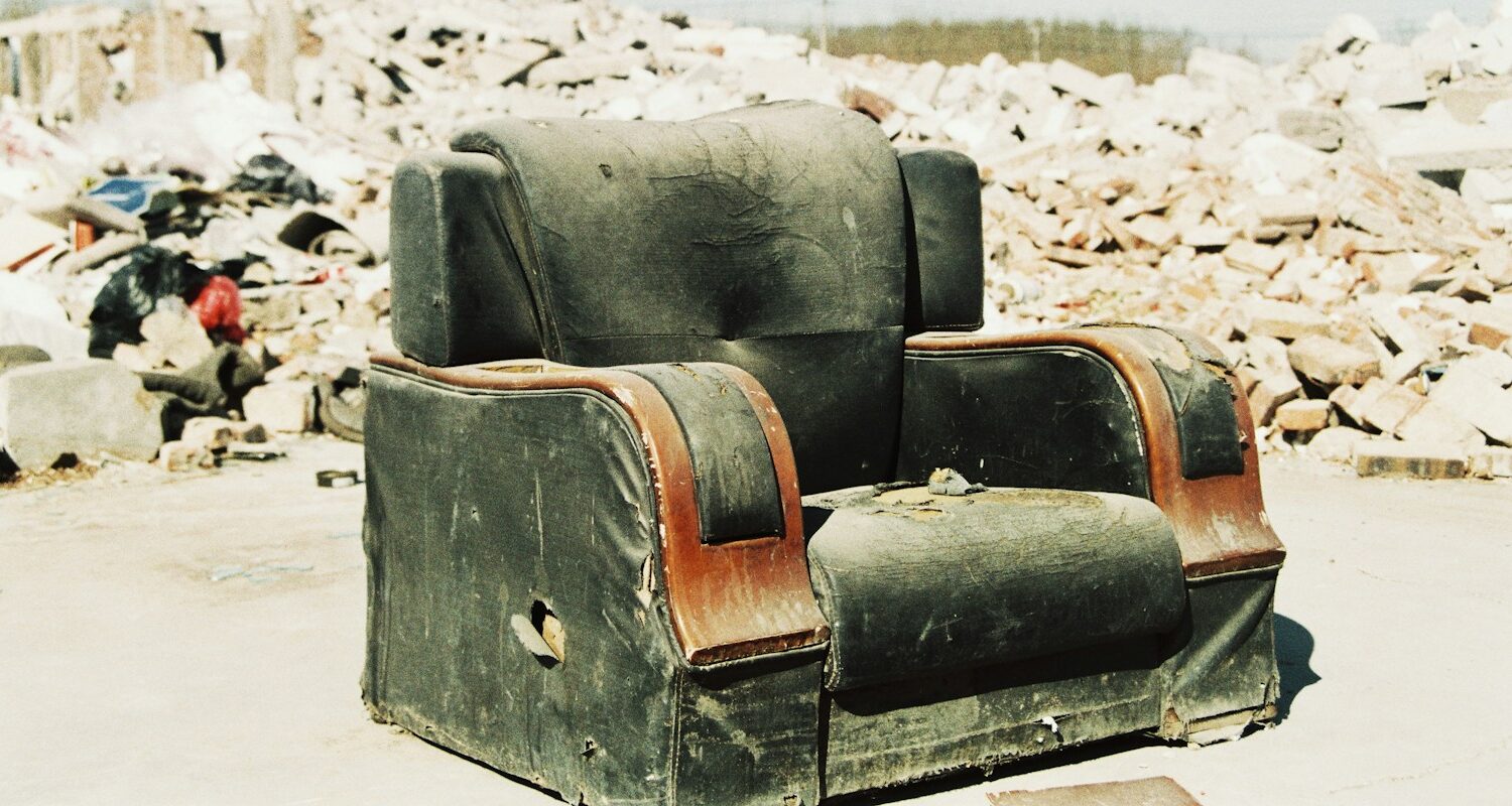 an old chair sitting in front of a pile of rubble