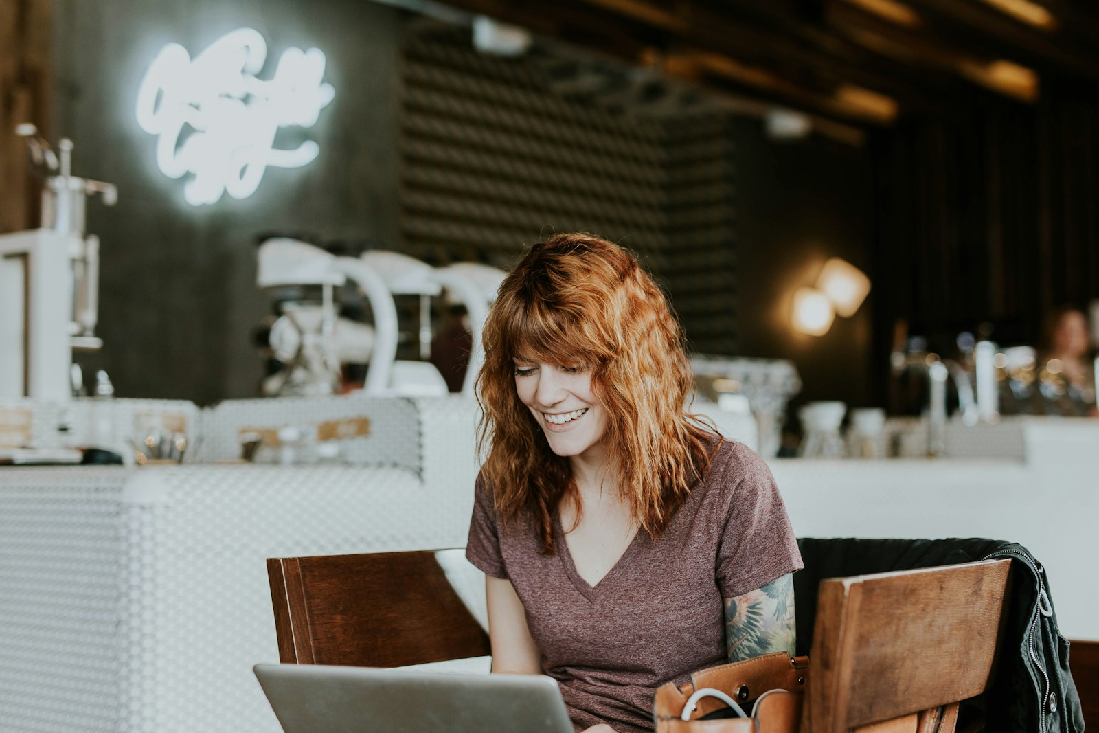 woman sitting on brown wooden chair while using silver laptop computer in room -brand loyalty app